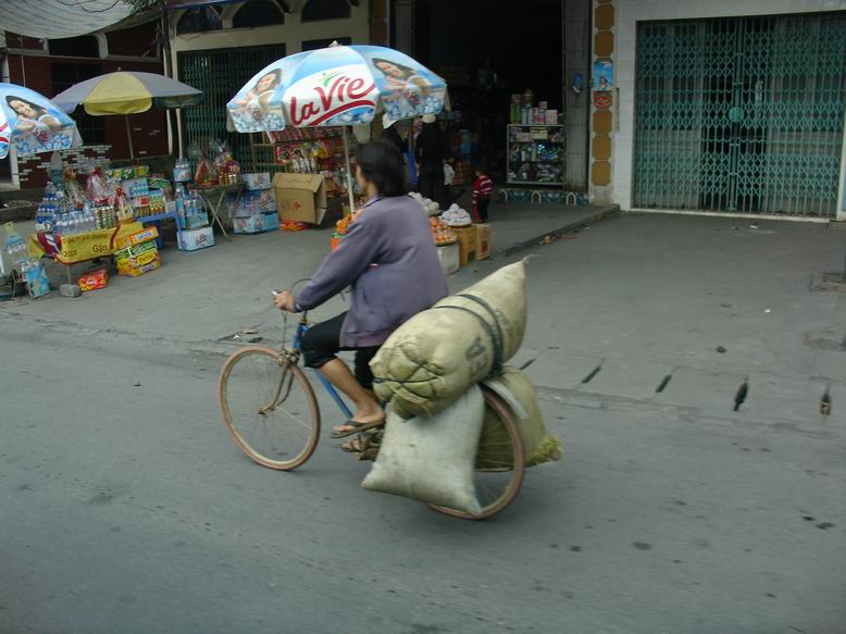 Kolo je nejdulezitejsi nastroj ve Vietnamu.
V pozadi je videt to co skoro kazdy dum ma v prizemi - maly obchudek s cimkoliv.